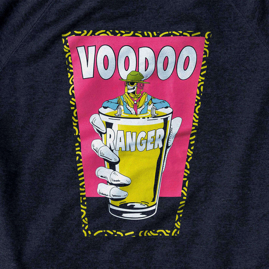 Close-up of laser printed, illustration on the back. It's a pint glass shape with a yellow patterned outline, filled with hot pink three quarters of the way down, and grey the remaining quarter. A large Voodoo hand holds a smaller pint glass filled with yellow liquid, and Voodoo Ranger is soaking in the glass with his arms resting on the side of the pint glass. The word Voodoo is large behind the Voodoo Ranger, and the word Ranger is smaller and printed on the pint glass. 