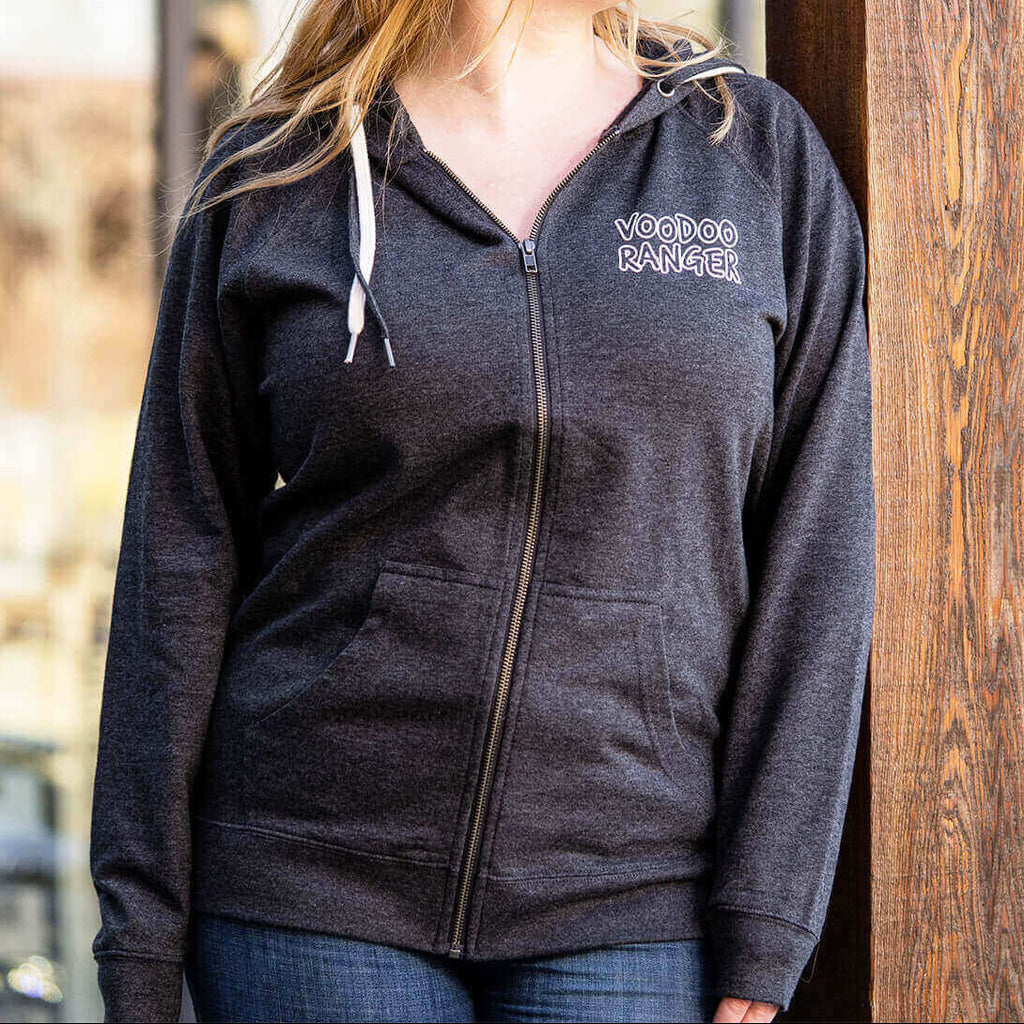 Woman wearing zip hoodie. It's a relaxed fit with the white outlined Voodoo Ranger logo laser printed on the front upper left side. 